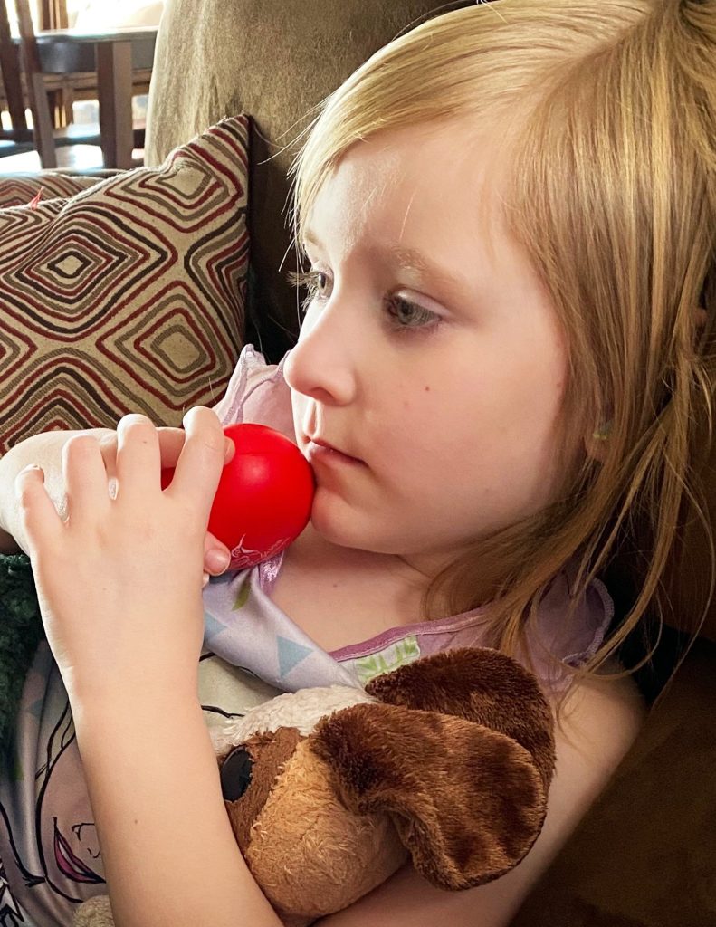 Little girl hugging heart shaped stress toy